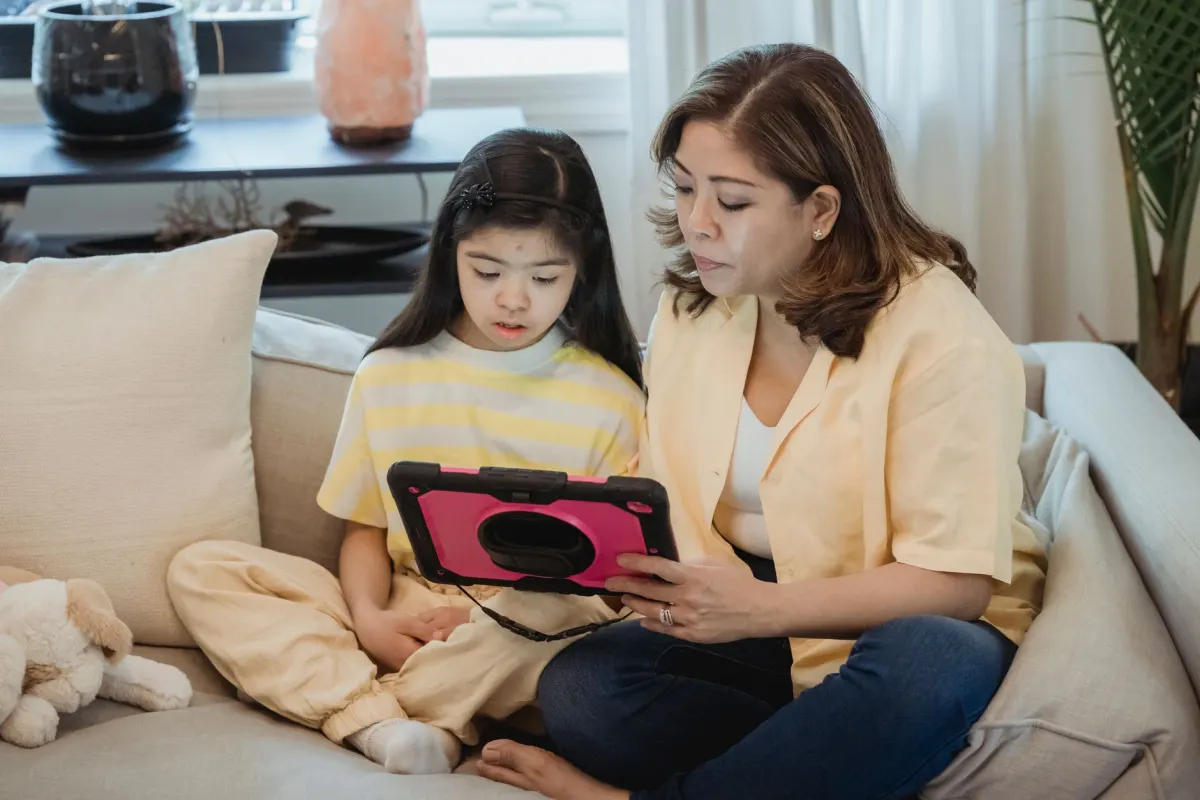 Ein Elternteil und ein Kind schauen sich gemeinsam ein Video auf einem Tablet an, ein Sinnbild für das Vertrauen, das Eltern brauchen, bevor sie Kinder unbeaufsichtigt zuschauen lassen.