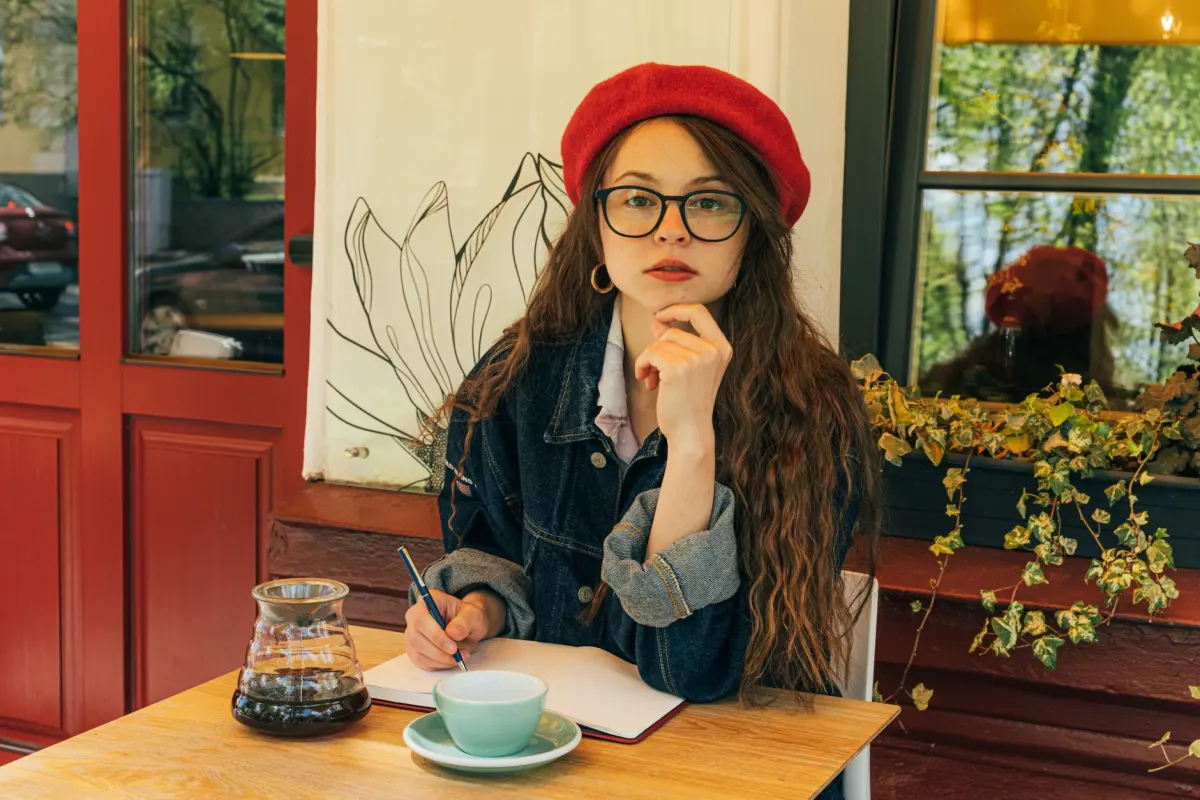 Uma mulher escreve num caderno numa mesa de café, refletindo a abordagem de história pessoal por trás de uma bio narrativa.