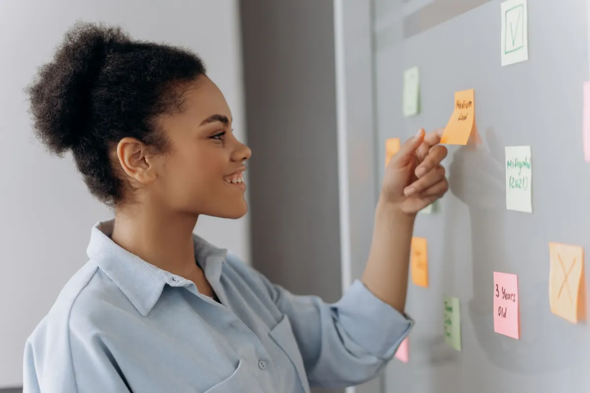 Une personne dispose des post-it en séquence, illustrant comment chaque diapositive de carrousel doit porter une seule idée avant que la suivante ne commence.
