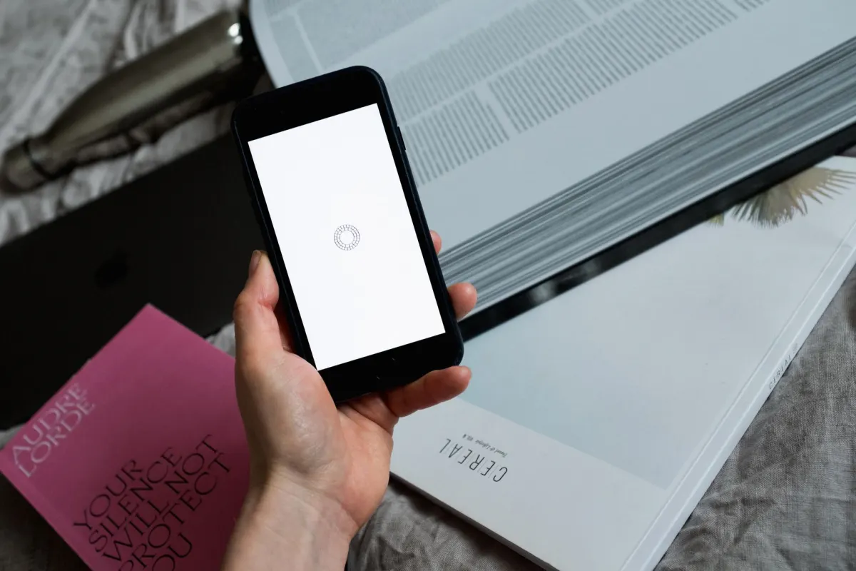 A phone displaying a loading spinner on a desk, standing in for the wait while a video container transcodes.