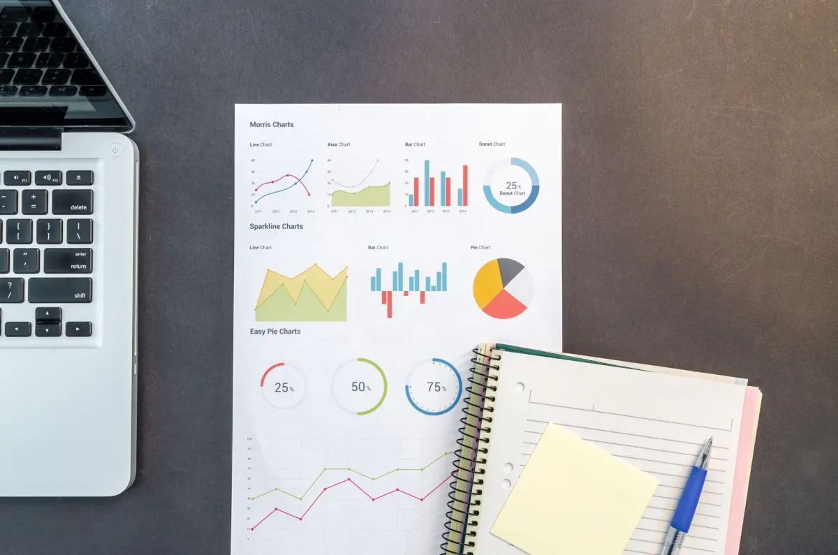 Un ordinateur portable affichant des graphiques à barres à côté d'un carnet, en écho à la comparaison entre outils d'analyse.