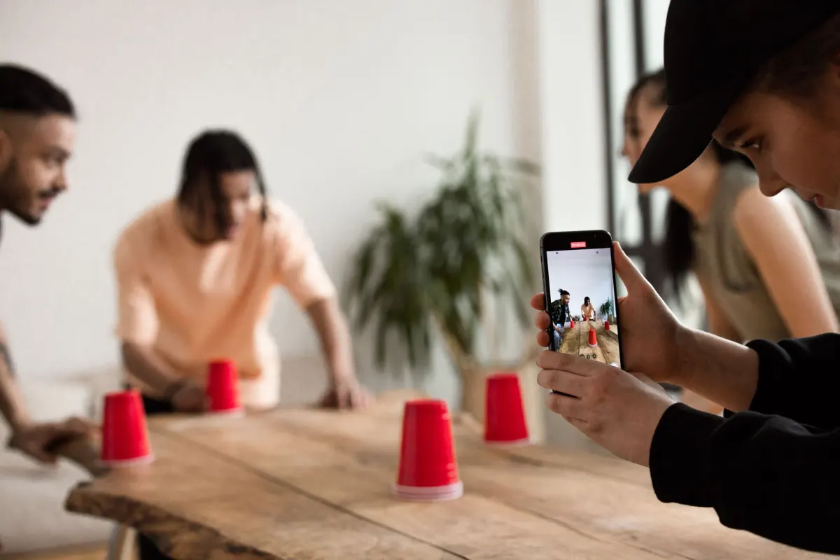 Amigos filmando um vídeo rápido com um smartphone, mostrado aqui porque as hashtags em alta seguem o mesmo tipo de atenção passageira e em tempo real.