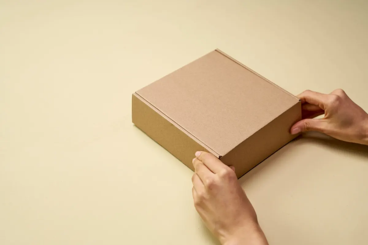 Des mains ouvrent un colis en carton lors d'un unboxing, à côté de la section sur les tests produits.