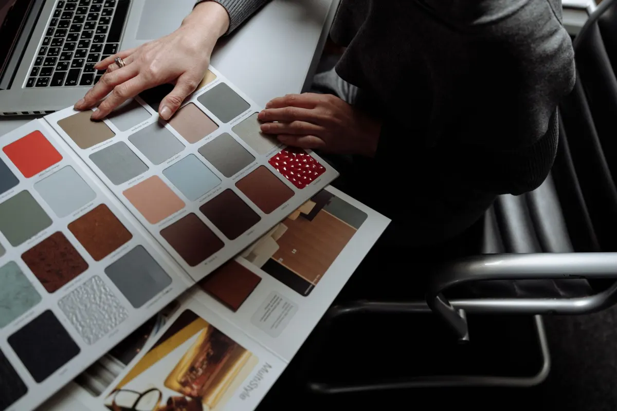 Ein Designer prüft Farbmuster neben einem Laptop, was die Markenkonsistenz-Arbeit hinter Story-Anzeigenvorlagen widerspiegelt.