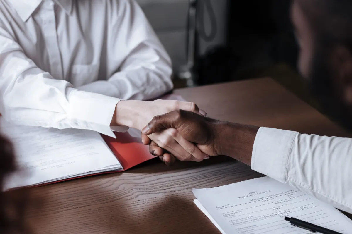 Dois profissionais apertam as maos apos uma entrevista de emprego, o momento que uma mensagem de follow-up bem cronometrada pode aproveitar.