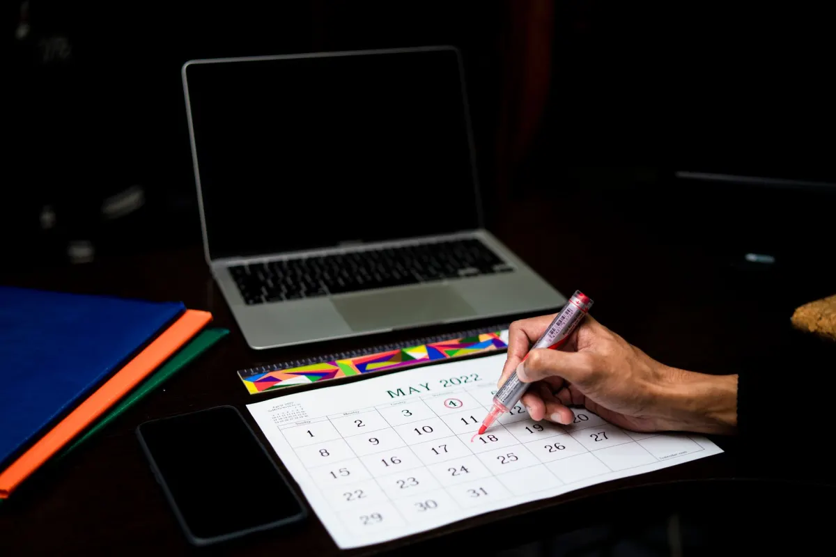 Uma pessoa verifica o horario e o calendario no laptop, o tipo de decisao de tempo da qual depende escalar os follow-ups.