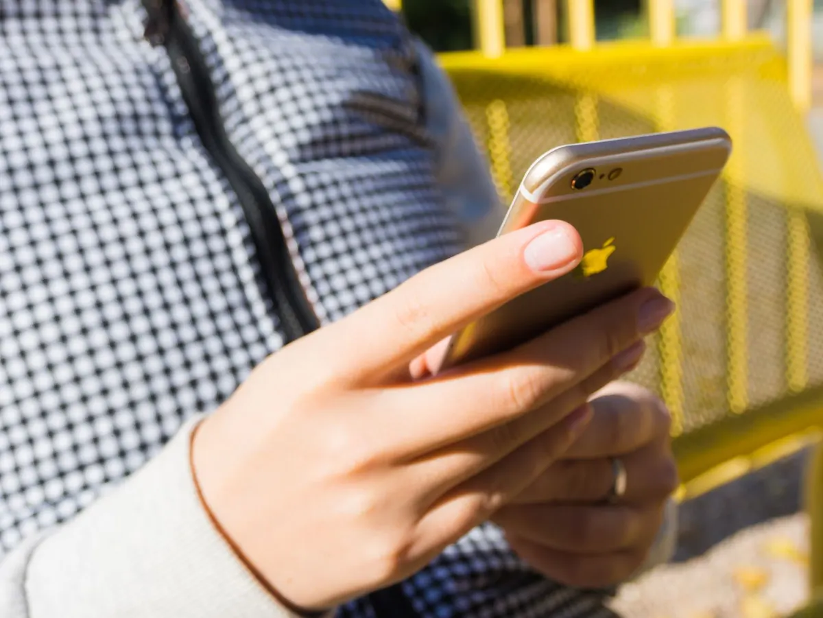 Eine berufstätige Person prüft während der Arbeitszeit eine Benachrichtigung auf dem Handy, passend zum Hinweis auf das richtige Timing beim Versand von InMails.