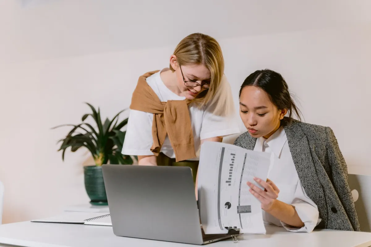 Des collègues regardent un ordinateur portable ensemble, illustrant comment l'advocacy des employés multiplie la portée d'une marque sur LinkedIn.