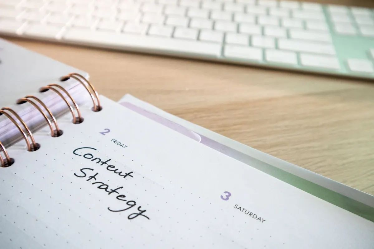 Une personne planifie un calendrier de contenu dans un carnet, illustrant la régularité qu'exigent les bonnes pratiques du marketing LinkedIn.