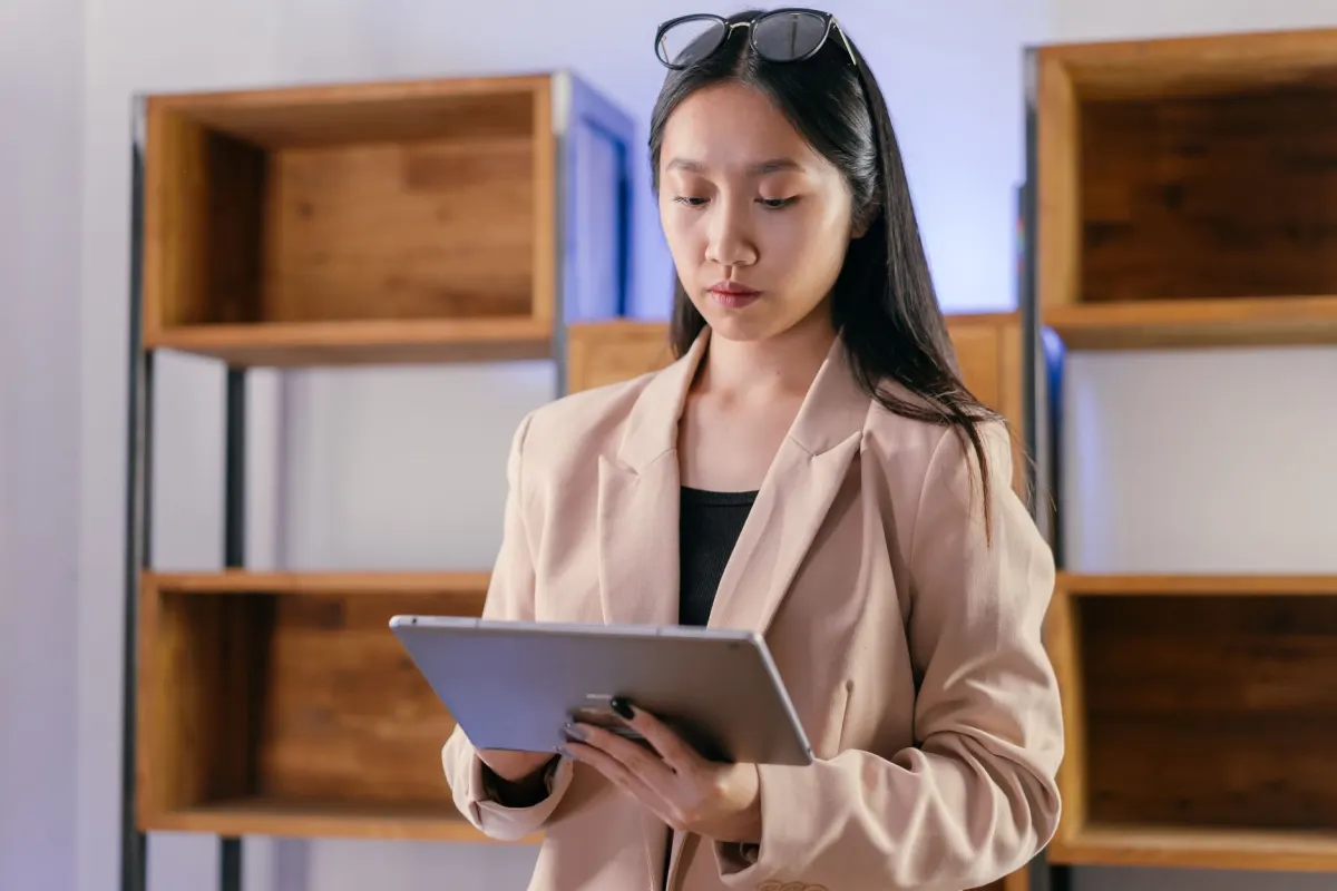 Une professionnelle lit du contenu sur une tablette à son bureau, le type d'audience concentrée que touchent les newsletters LinkedIn.
