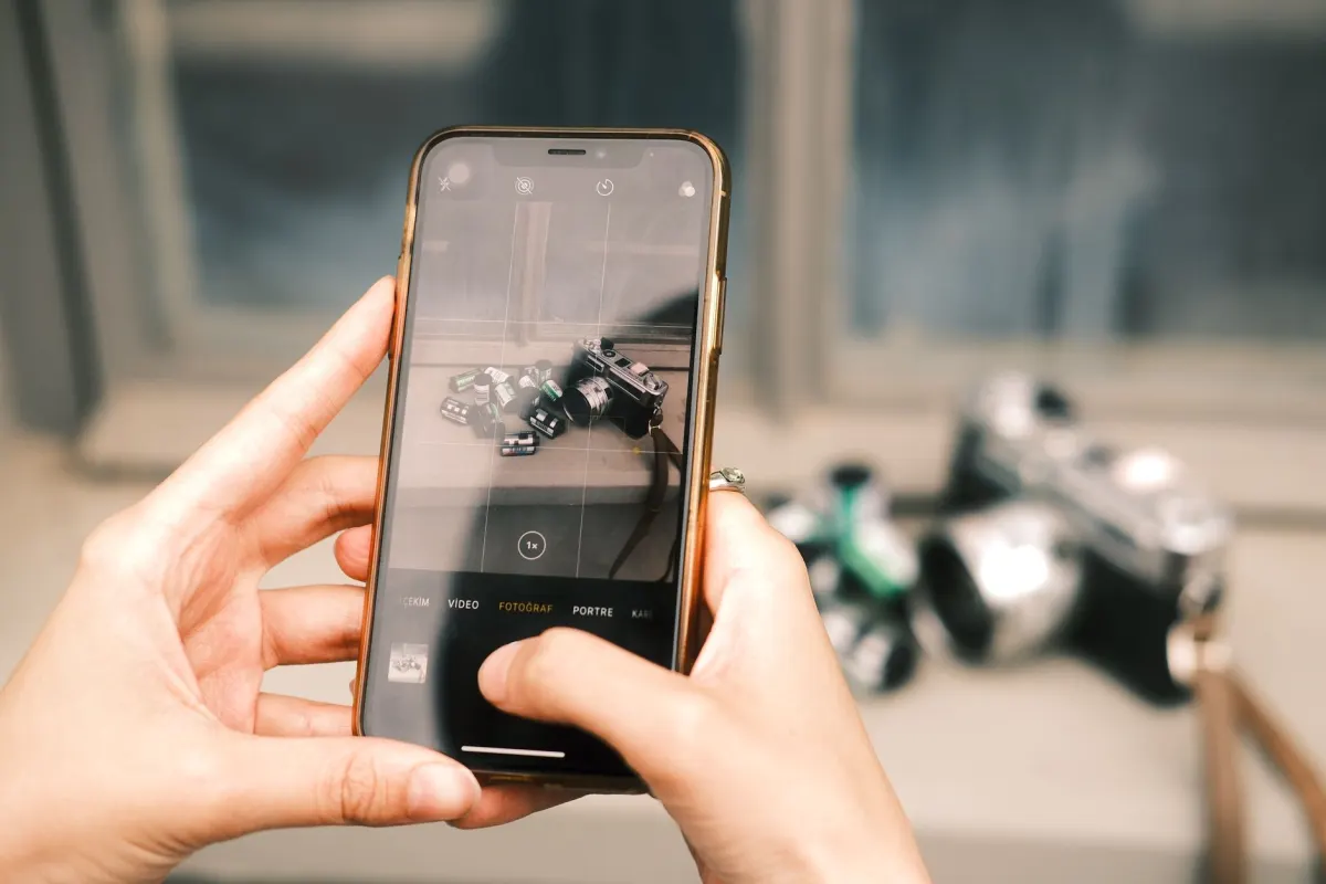 Una persona sostiene un teléfono para fotografiar una diapositiva de una presentación en una conferencia, mostrando cómo la app móvil captura contenido de eventos en vivo.