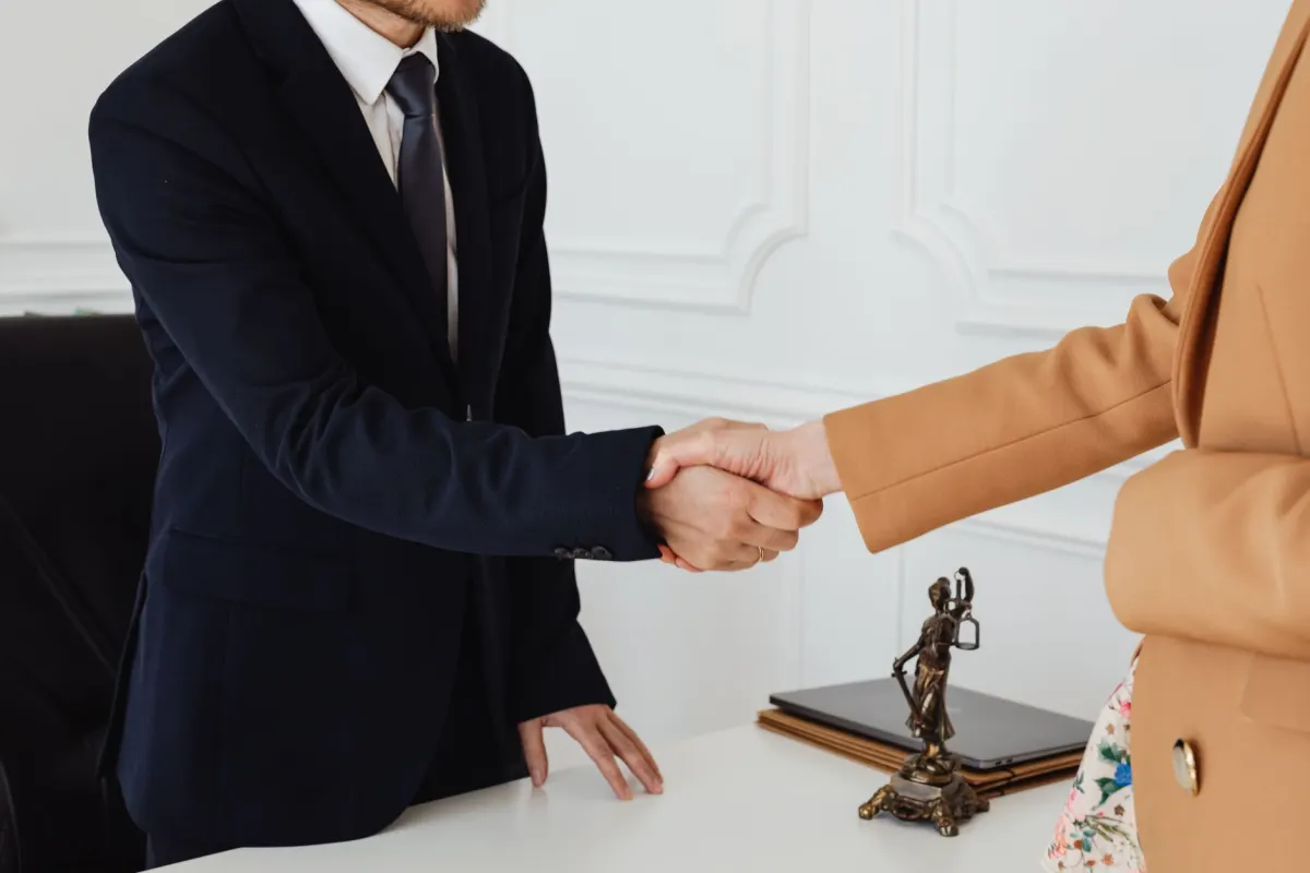 Dos colegas se dan la mano en una oficina, en referencia a las actividades de construcción de relaciones del cuarto pilar del SSI.