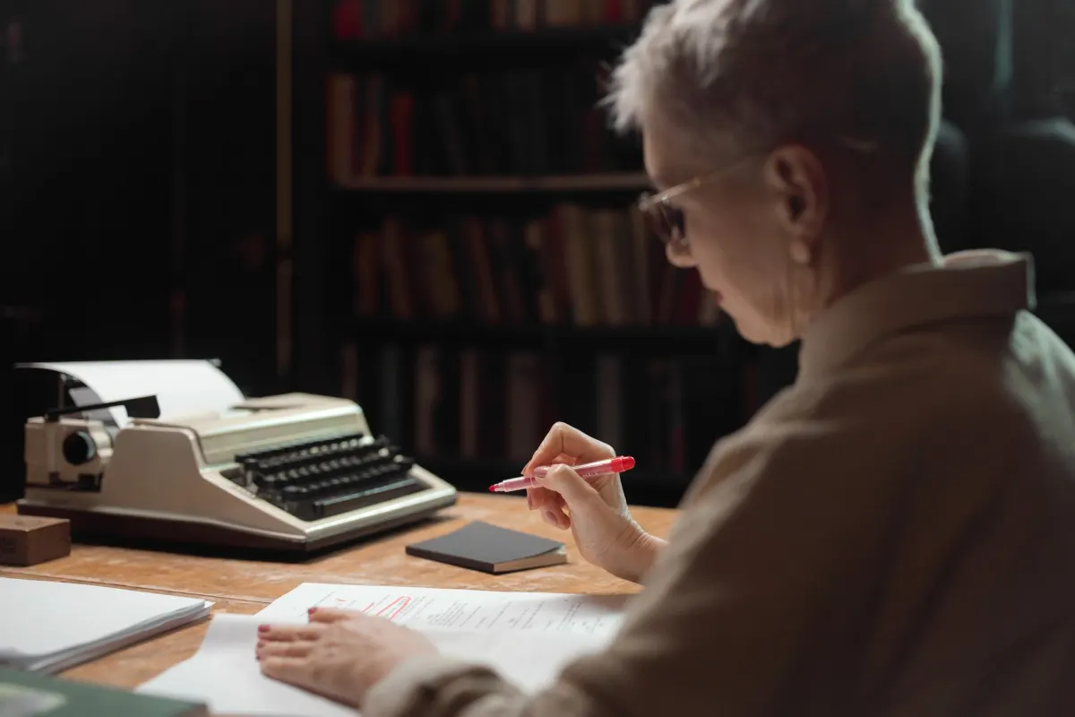 An editor marking up printed pages with a pen before approving them, like checking a draft before it goes public.