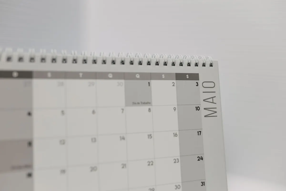 A wall calendar on a desk stands in for the queue of scheduled posts an account manages over time.