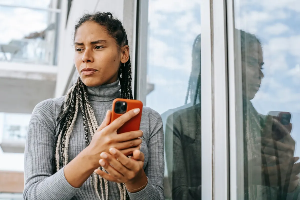 Una mujer frunce el ceño ante su smartphone, como imagen del momento en que una cuenta de Instagram resulta ser del tipo equivocado o una skill guardada se ha quedado obsoleta.