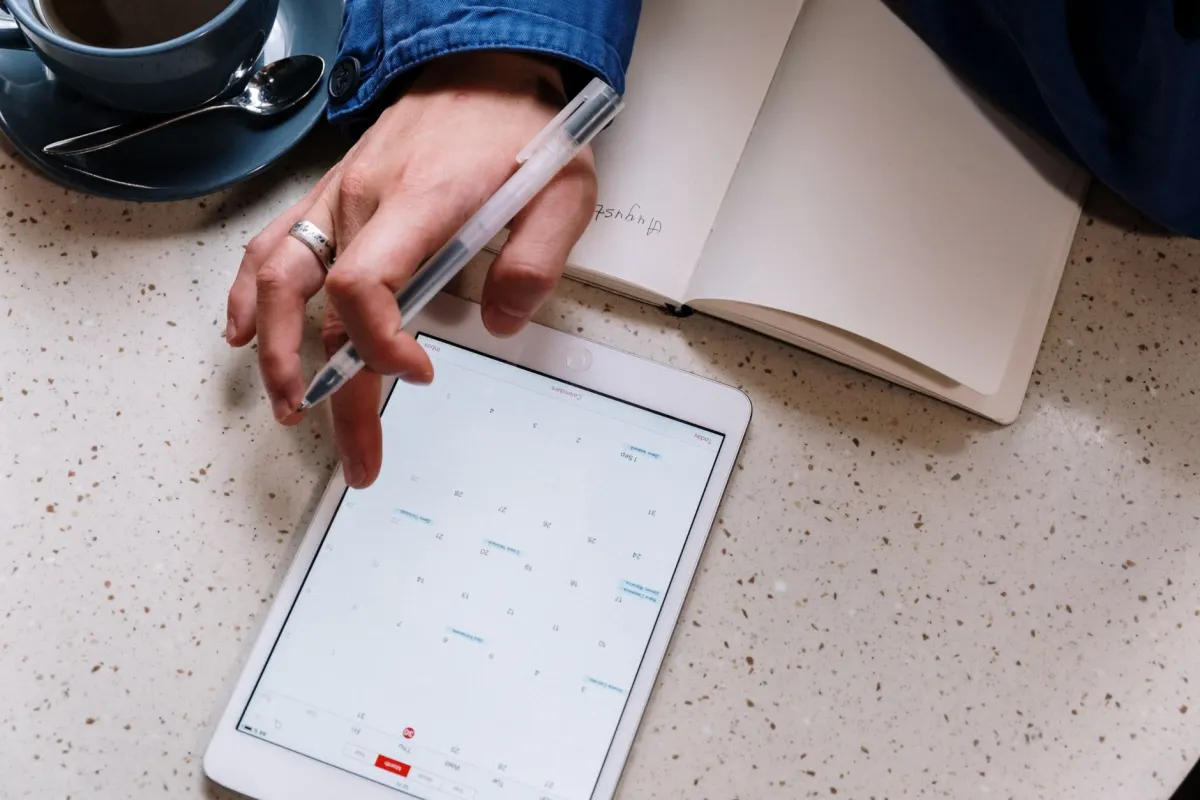 Eine Person plant eine Woche voller Beiträge im Tablet-Kalender, passend zur in diesem Abschnitt verglichenen Massenplanung.
