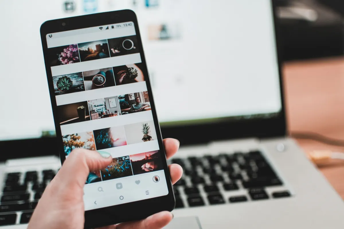 Una mano recorriendo un feed de redes sociales en un smartphone, la pantalla donde aparece una tarjeta de vista previa de enlace.