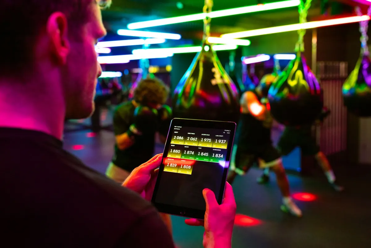 Un instructeur de fitness consulte une tablette à l'accueil, le genre de flux de réservation sur mesure qu'une plateforme open source peut être conçue pour reproduire.