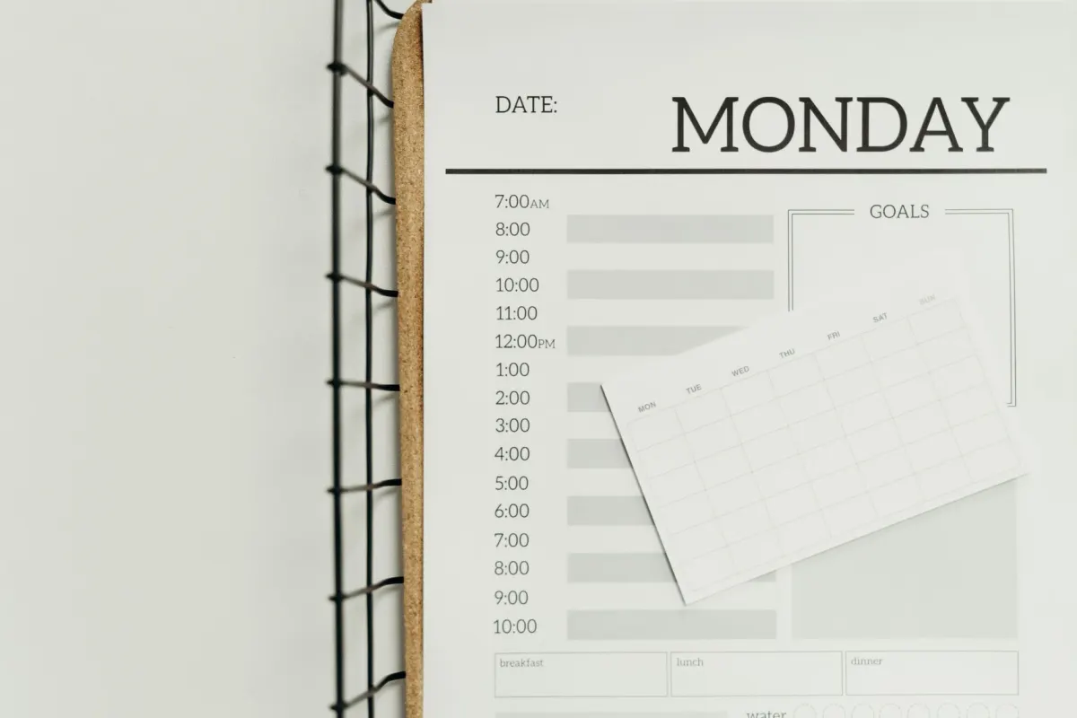 A paper weekly planner on a desk beside a coffee cup, standing in for recurring tasks that run on a schedule.