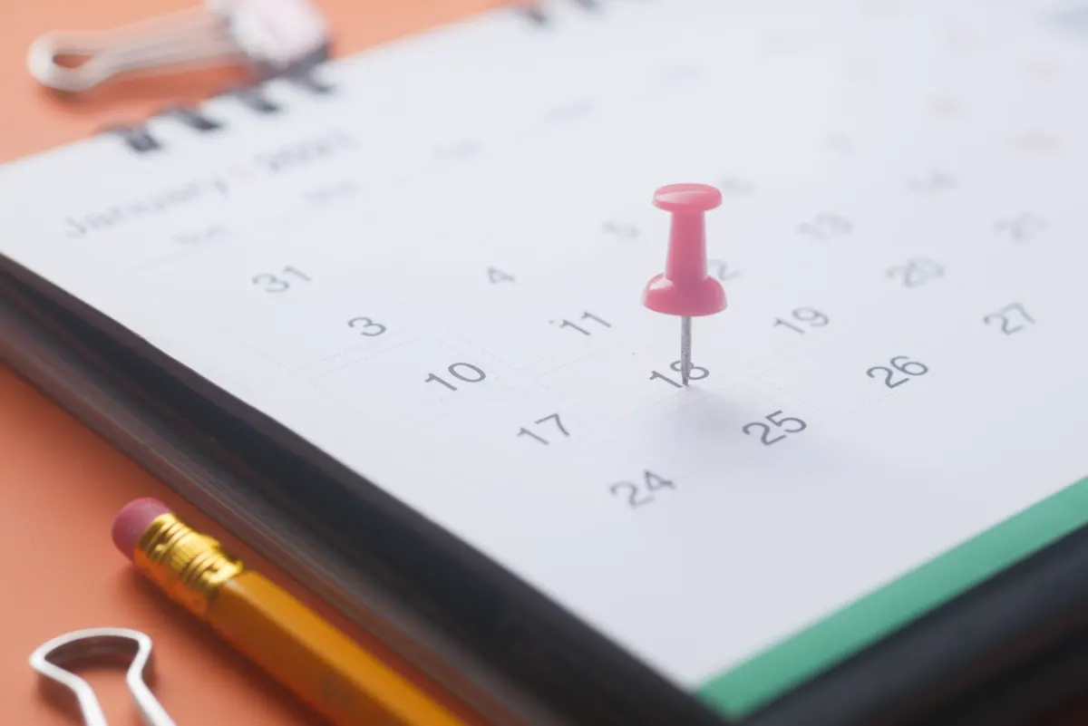 A paper wall calendar with dates marked, illustrating a thread booked as a series of posts spaced over time.