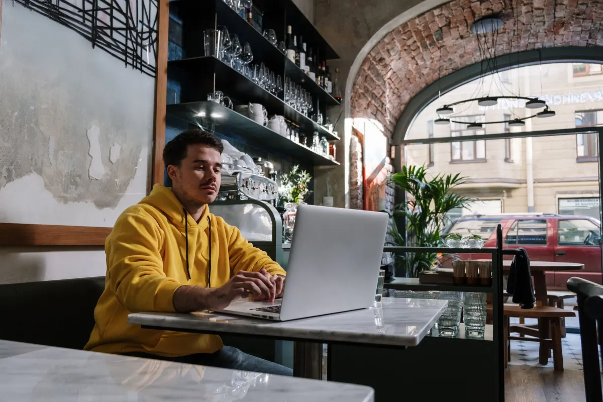 Uma pessoa trabalhando em um laptop em um ambiente casual, refletindo o fluxo de trabalho descontraído e de qualquer lugar descrito nesta seção.