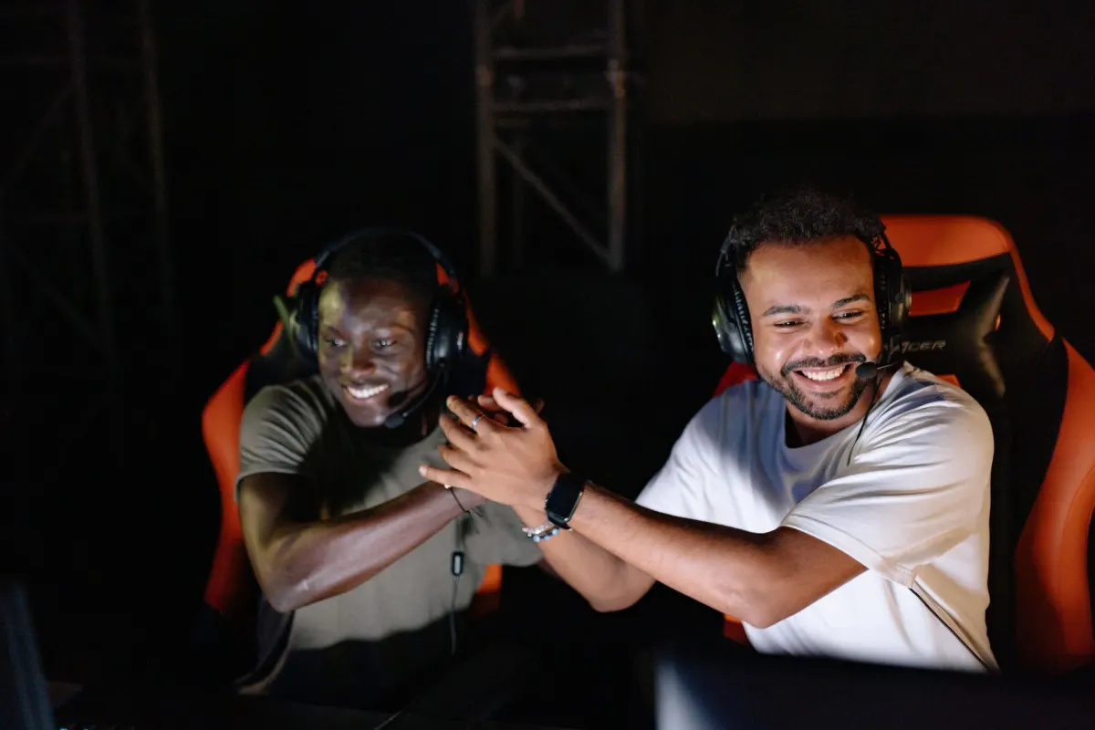 Dos jugadores con auriculares celebran una victoria, en referencia al ejemplo de comunidad FPS usado para explicar los niveles de precios en esta sección.