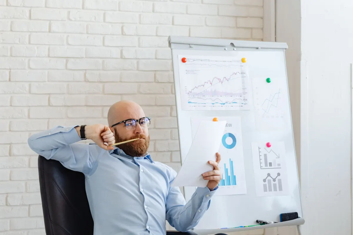 Eine Marketing-Fachkraft prüft Leistungsdiagramme am Schreibtisch, wie sie ein Analytics-Dashboard liefert.
