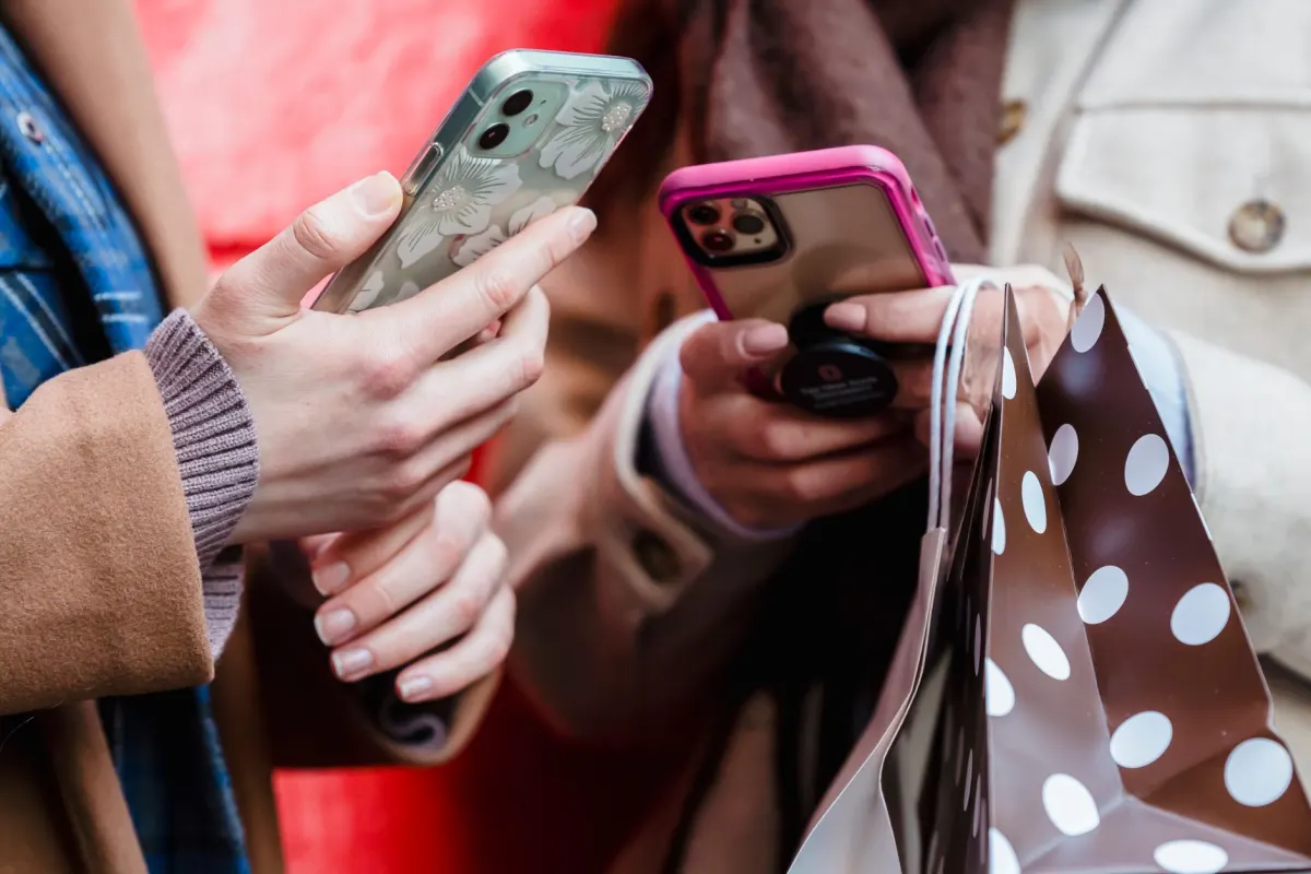 Uma pessoa confere o celular enquanto carrega sacolas de compras, o momento que os posts com tags de produto tentam captar.