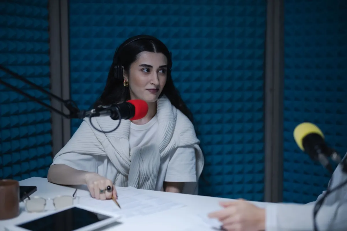 Uma apresentadora grava um episódio de podcast em um microfone de mesa, o tipo de material-fonte longo do qual um framework de reaproveitamento parte.