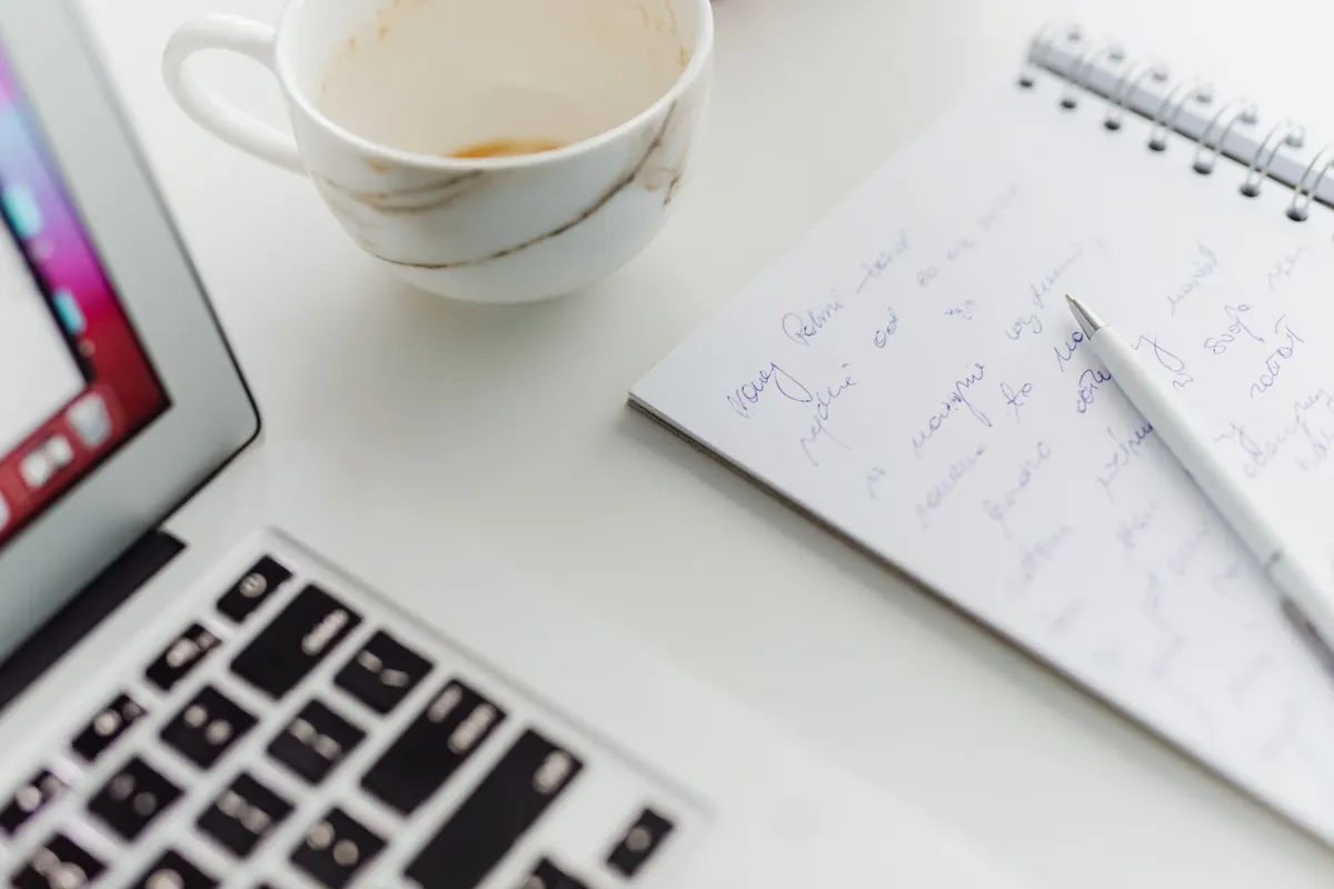 Un portátil y un café en un escritorio durante un bloque de trabajo matutino tranquilo, el tipo de espacio usado para la creación por lotes de contenido semanal.
