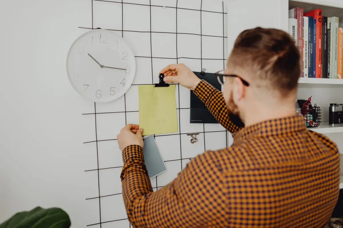 Eine Person blickt auf eine Wanduhr im Büro, eine Erinnerung daran, die Geräte-Zeitzone zu überprüfen, bevor ein TikTok-Beitrag zur falschen Stunde veröffentlicht wird.