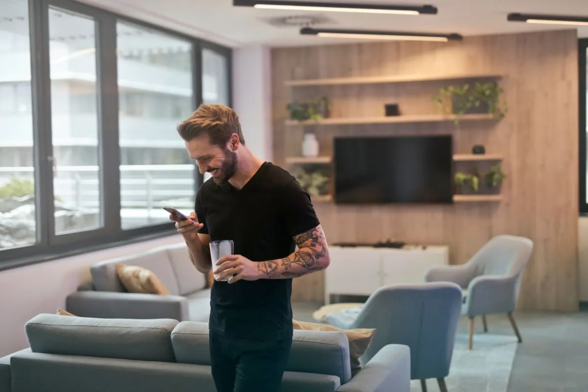 Eine Person laechelt beim Tippen auf dem Handy, genau die lockere Nachricht, in der ein Shrug-Emoji oft auftaucht.