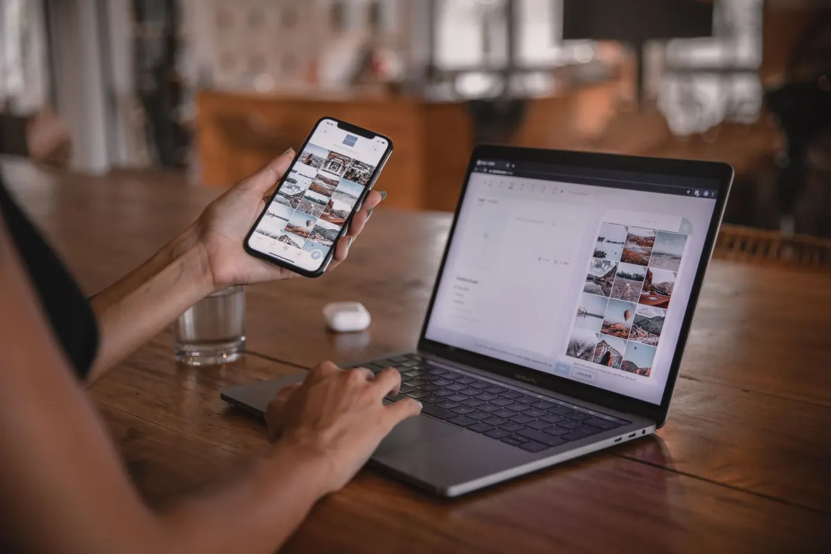 Eine Social-Media-Managerin prueft Beitraege auf Laptop und Handy und entscheidet, wie locker der Markenton sein soll.