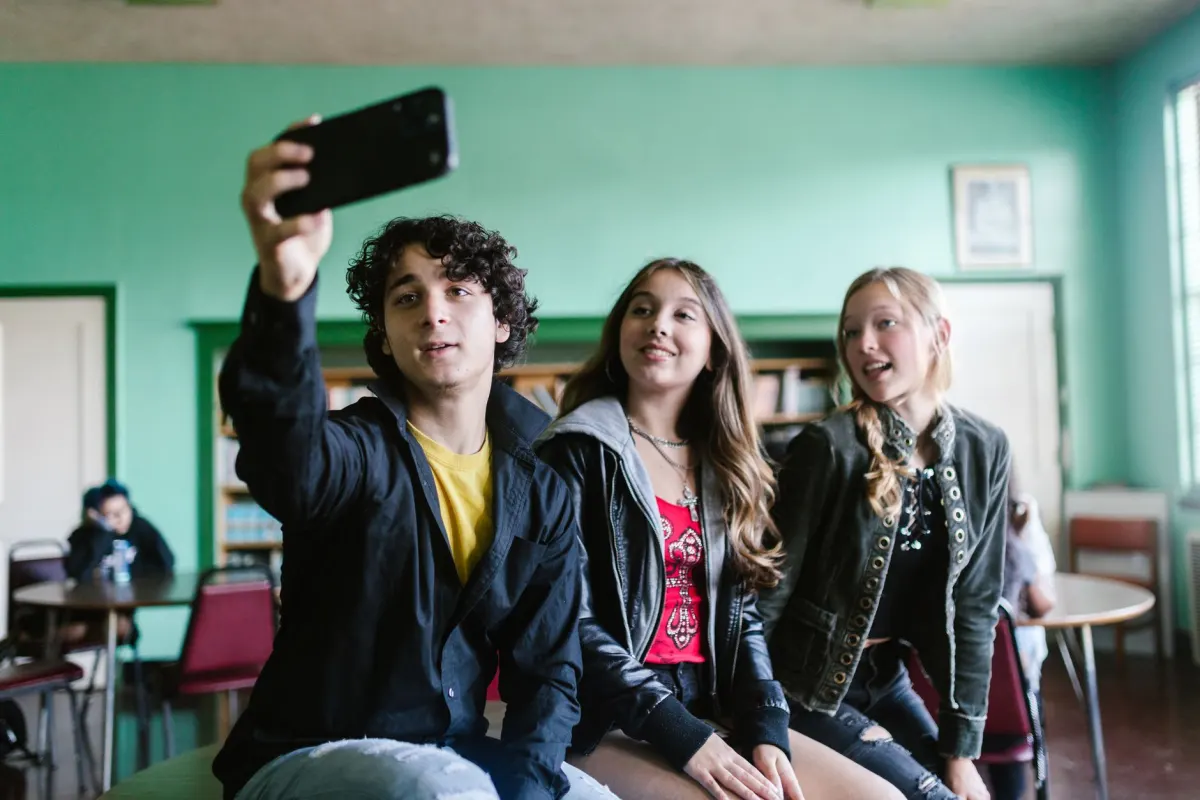 Ein Teenager hält ein Handy hoch, um ein Selfie zu machen, genau die Art von beiläufigem Moment, den Marken mit AR-Linsen und Filtern einfangen wollen.