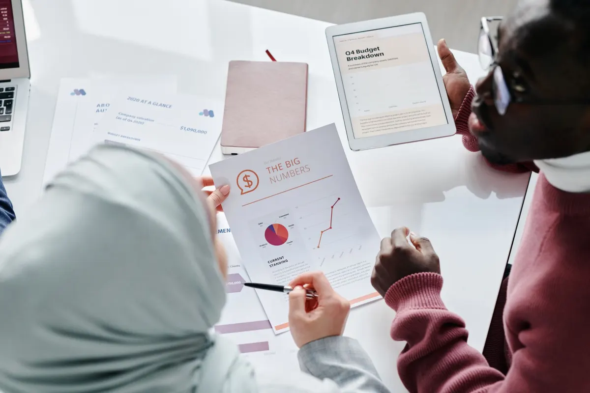 Ein kleines Team bespricht Diagramme auf einem Laptop während eines Meetings, passend zur Berichtsstruktur, die dieser Abschnitt beschreibt.