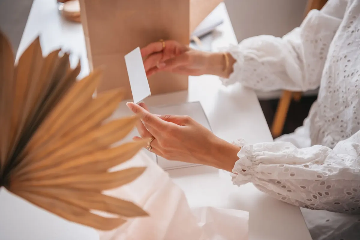 Une femme sourit en ouvrant un colis cadeau, représentant une gagnante qui reçoit son prix.