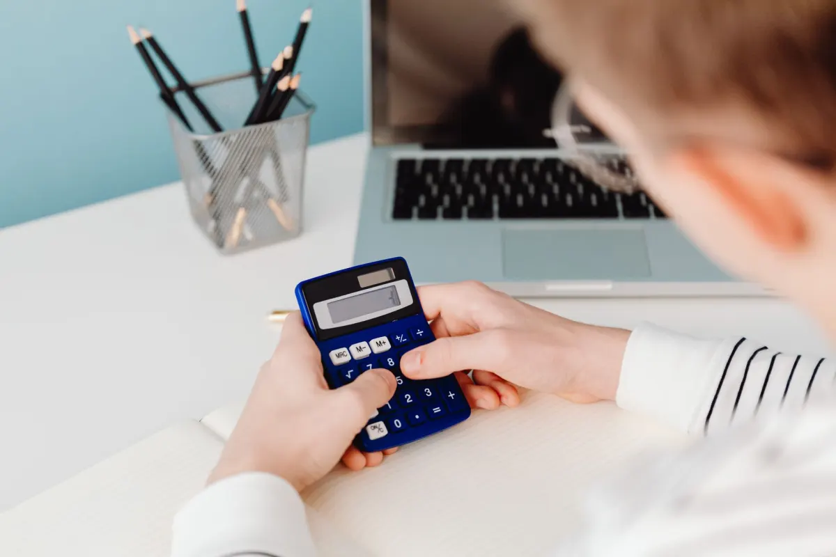 Une personne calcule des chiffres sur un ordinateur portable à un bureau, à côté de la section sur le calcul du taux d'engagement par abonnés.
