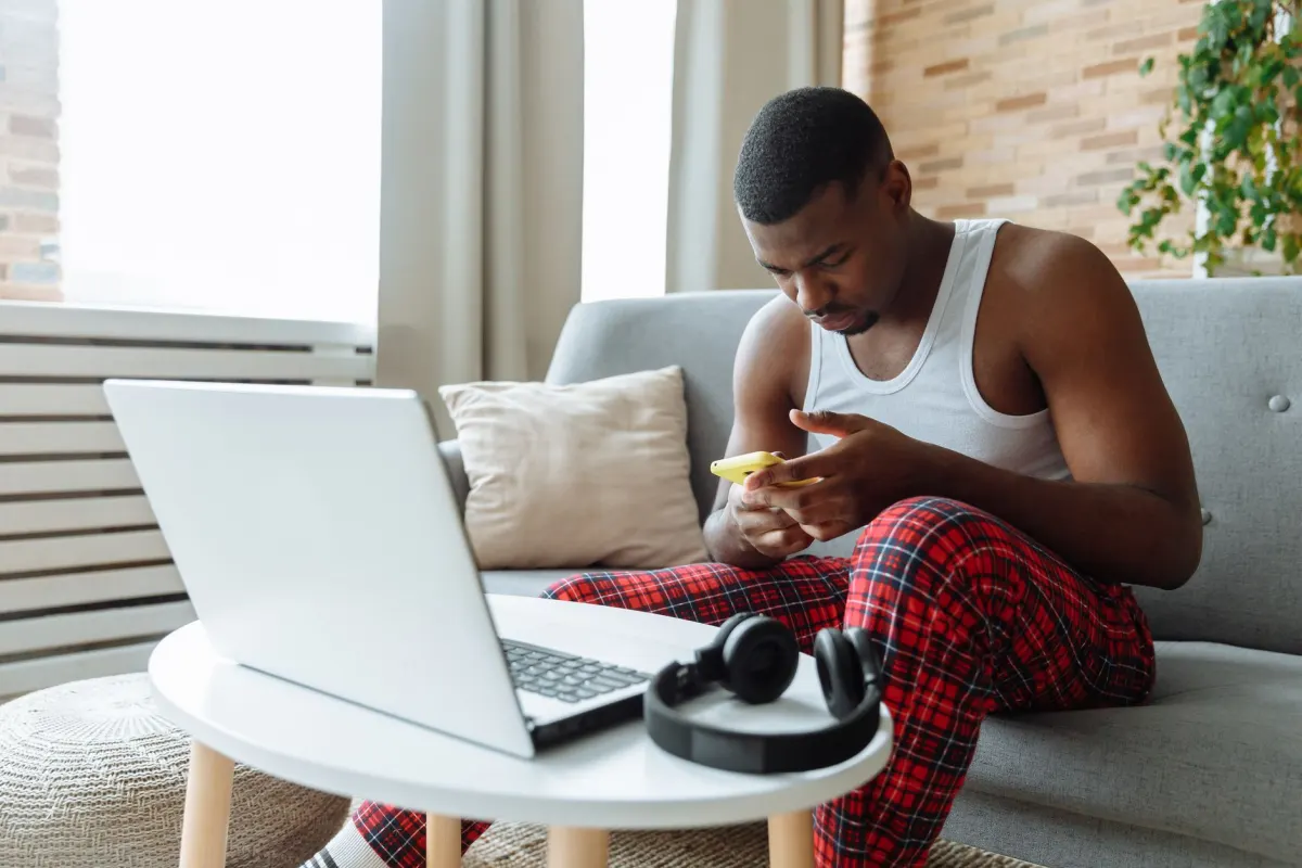 Eine Creatorin sitzt auf einem Sofa und prüft Kennzahlen auf ihrem Handy, passend zum Vergleich zwischen Engagement-Rate und Followerzahl.