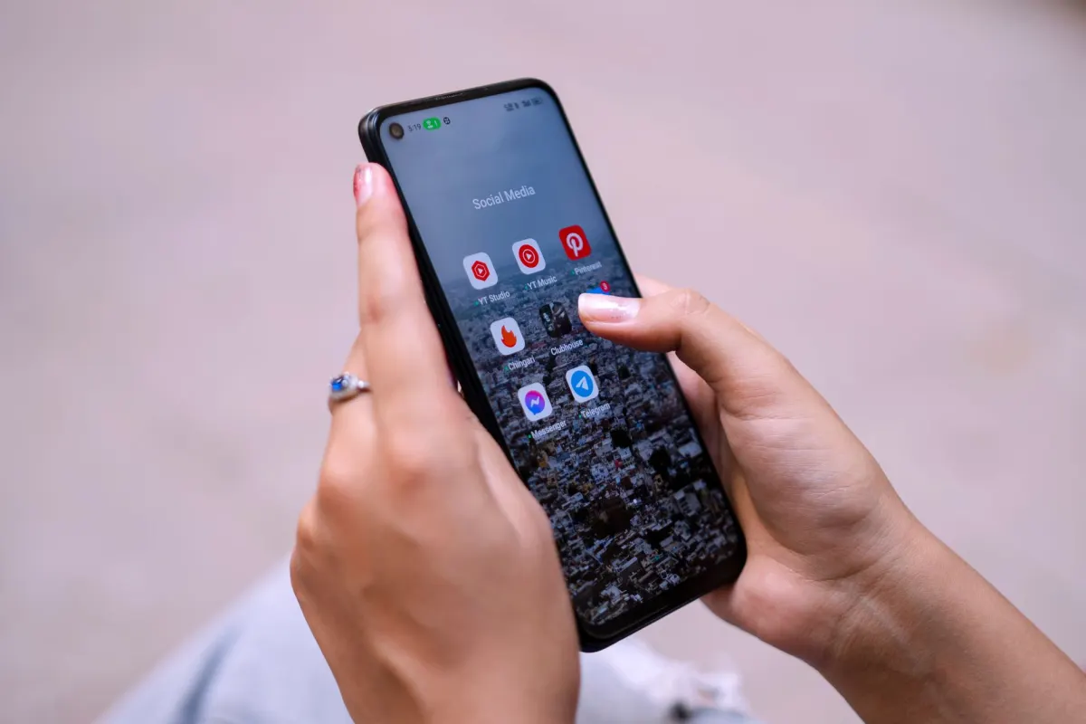 Uma pessoa navega por perfis de redes sociais no celular, ilustrando a diferenca entre handle e nome de exibicao.