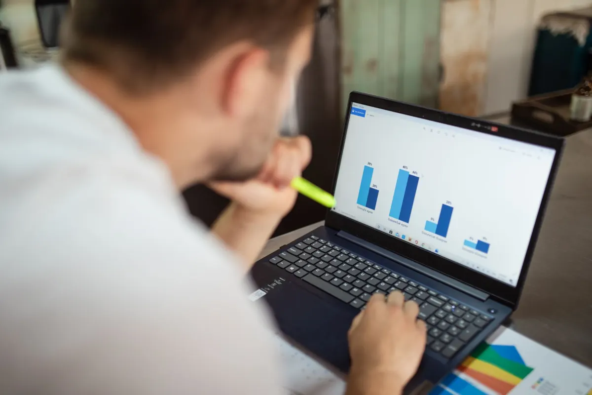 Un analyste consulte des graphiques sur un ordinateur portable, le type de travail de reporting derrière la mesure de l'impact de l'écoute.