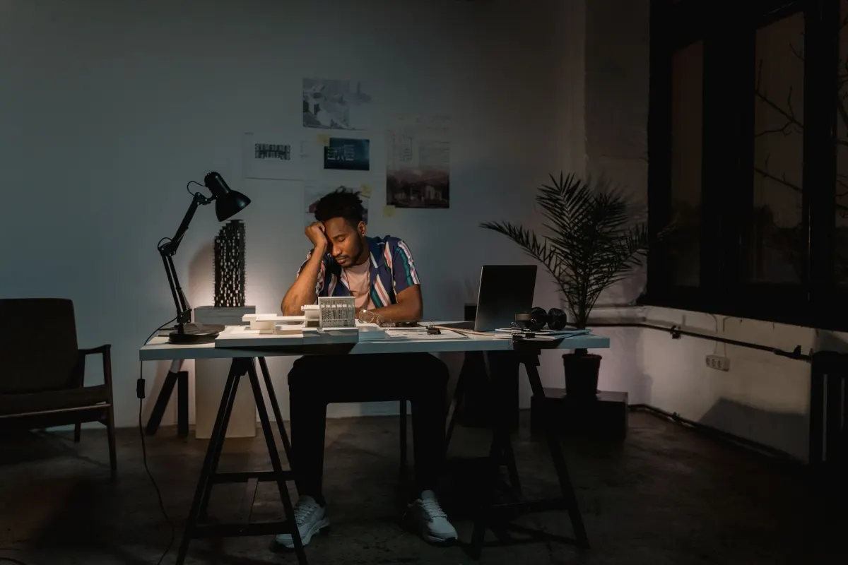 Eine Person reibt sich spät abends am Laptop die Augen, erschöpft vom ständigen Jonglieren mit Social-Media-Benachrichtigungen.