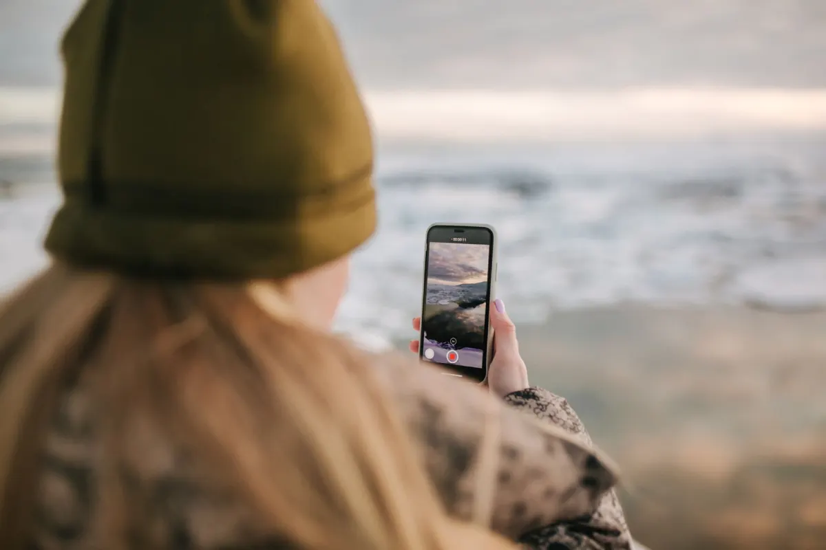 Ein Reisender filmt ein kurzes Video am Strand, die Art von Aufnahme, die zu einem Instagram Reel für ein Reisebüro wird.