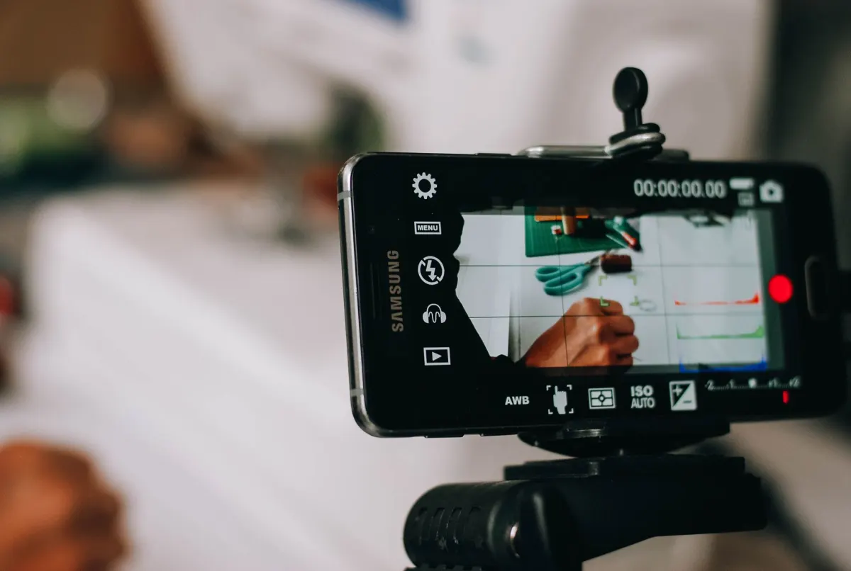 Um smartphone montado em um tripé grava um vídeo, o tipo de conteúdo que impulsiona as métricas de visualizações e tempo de exibição.
