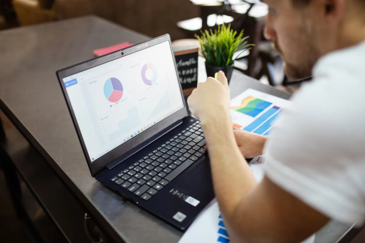 Uma pessoa analisa gráficos de desempenho em um laptop, o tipo de análise por trás do cálculo do ROI.