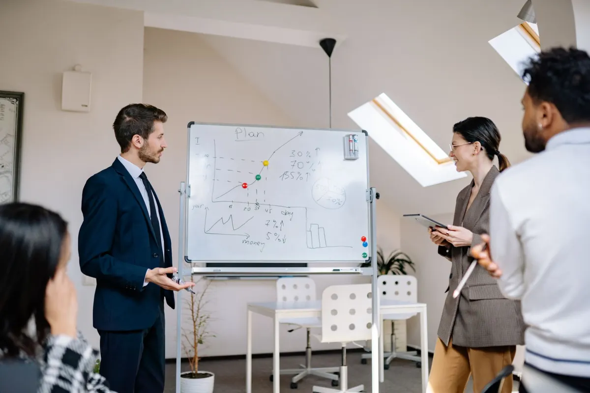 Une équipe se réunit autour d'une séance de planification au tableau blanc, le type de coordination nécessaire pour aligner contenu et canaux.