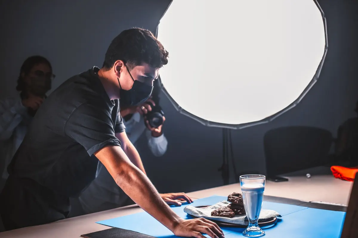Ein Fotograf richtet die Beleuchtung fuer ein Produkt auf einem gestylten Set ein, wie es eine Retail-Marke fuer ihren Instagram-Feed nutzt.