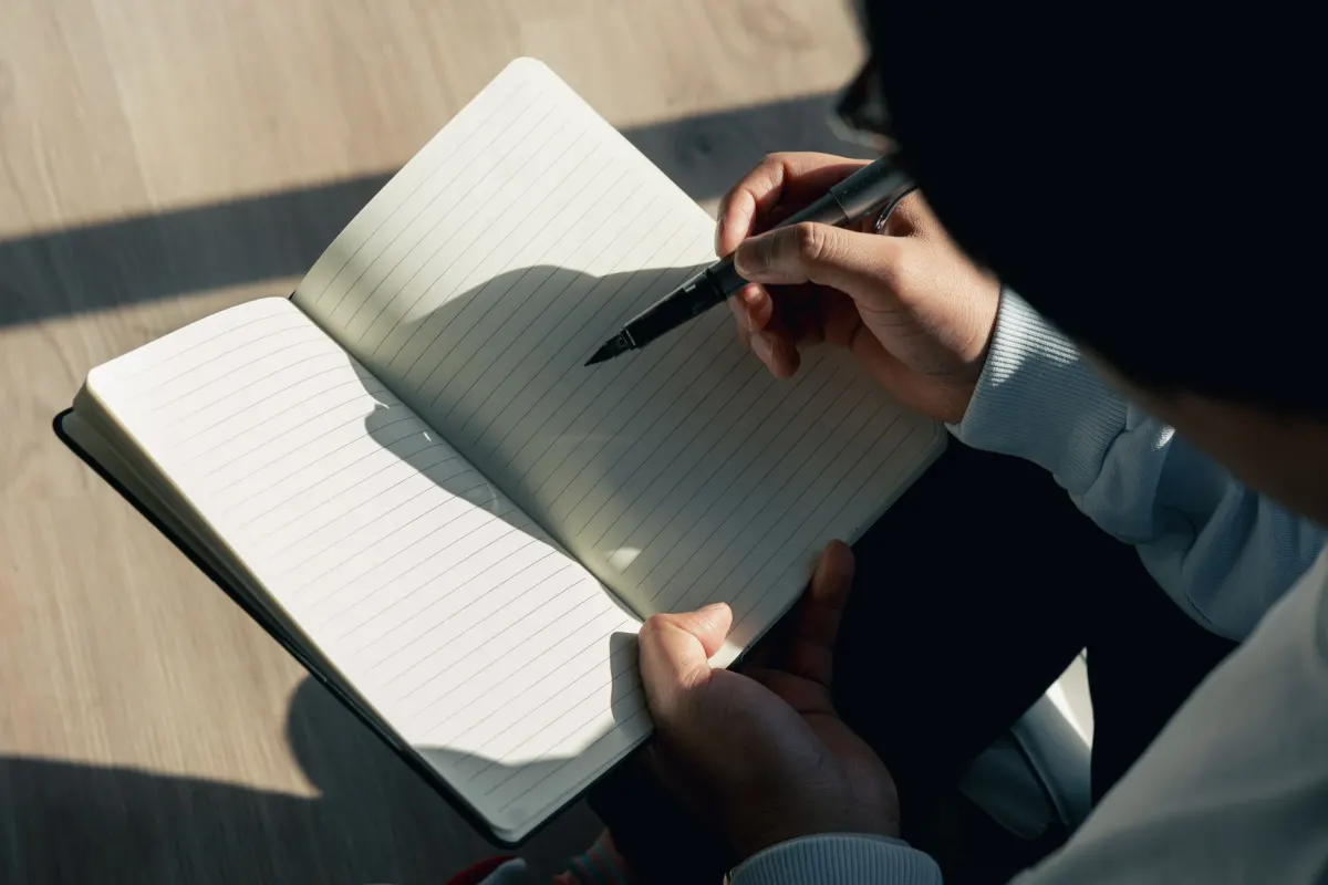 Eine Person notiert Ideen für Benutzernamen in einem Notizbuch beim Brainstorming.
