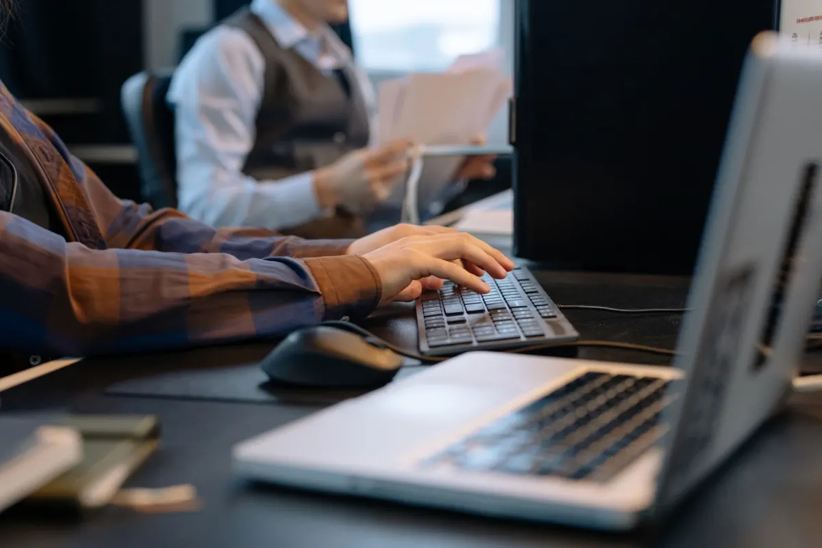 Una persona trabaja escribiendo en un portátil en la oficina, un recordatorio de que las publicaciones en el trabajo pueden rastrearse hasta los compañeros.
