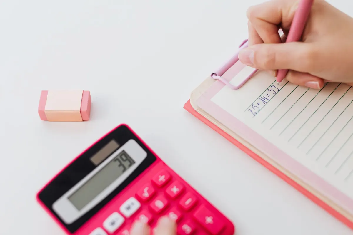 Une main fait des calculs sur papier, à l'image de la soustraction nécessaire pour répartir les caractères autour d'un lien raccourci.