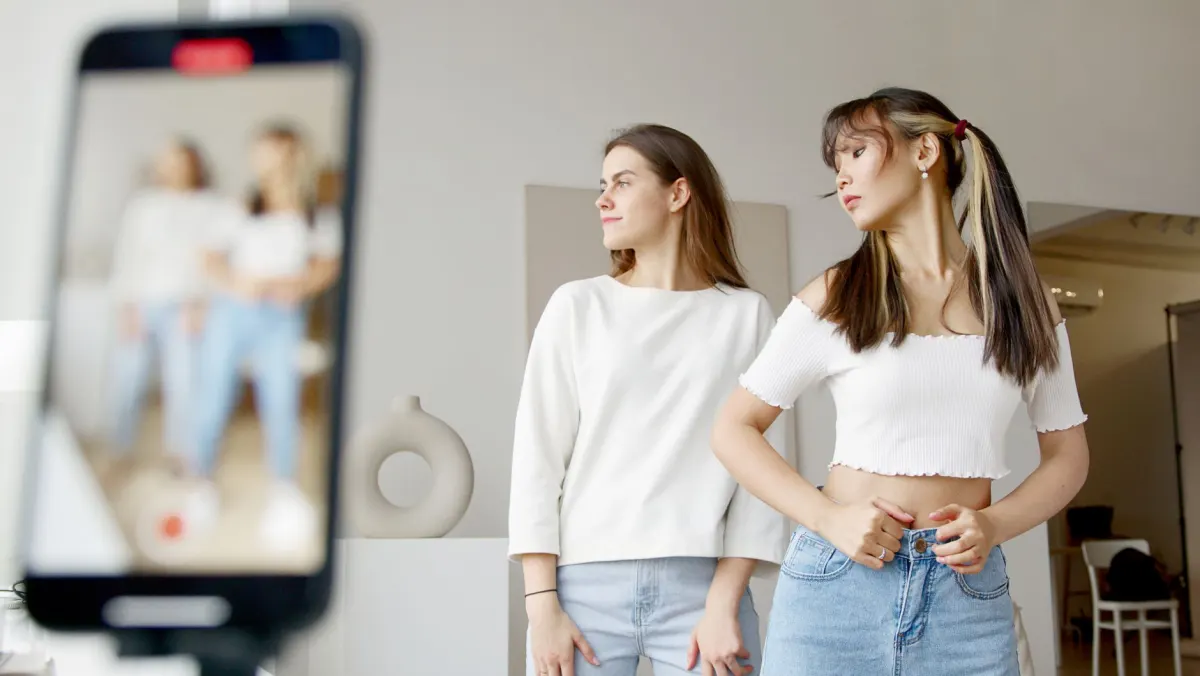 Eine Gruppe von Freunden filmt ein vertikales Video mit dem Handy, ein Beispiel für den Content, auf den demografische Recherche hinweist.